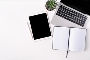 moderne witte tafel met een laptop, tablet en blanco notitieboekje