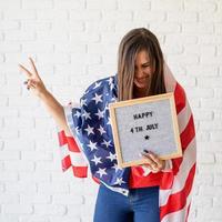 vrouw met amerikaanse vlag met letterbord met woorden gelukkig 4 juli
