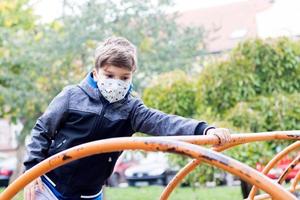 jongen met gezichtsmasker tijdens het spelen op de speelplaats. foto