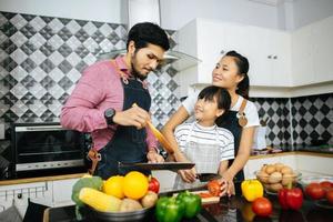 gelukkige familie helpt bij het koken van maaltijd samen in de keuken thuis. foto