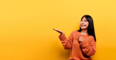 Aziatisch meisje mooi gekleed in een oranje vrijetijdskleding op gele achtergrond foto