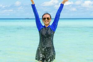 gelukkig Aziatisch tiener meisje Speel spatten water in de zee foto