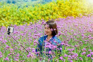 vrouw zijn nemen selfie in verbena bloem velden foto