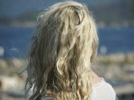niet herkenbaar meisje haar- van achter in voorkant van de zee foto