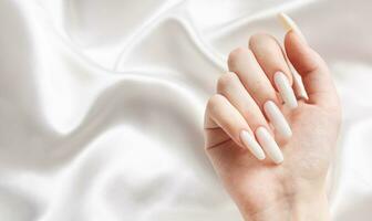 een vrouw handen met een manicure Aan hen, de nagels zijn geschilderd in een wit kleur. foto