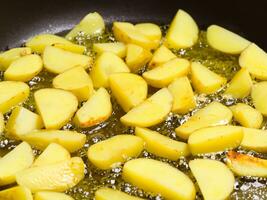 gebakken aardappelen met heet olie in een pan, dichtbij - omhoog foto