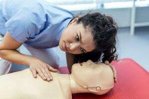 vrouw beoefenen cpr techniek Aan dummy gedurende eerste steun opleiding. eerste steun opleiding - cardiopulmonaal reanimatie. eerste steun Cursus Aan cpr pop. foto