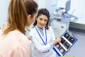 gynaecoloog tonen een afbeelding met echografie naar een jong vrouw geduldig, uitleggen de Kenmerken van vrouwen Gezondheid gedurende een medisch overleg in de kantoor foto