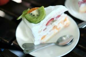 eigengemaakt bakkerij voor aardbei en kiwi kaas taart in wit bord. ontspanning met toetje in cafe foto