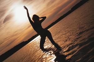 gelukkige zorgeloze vrouw genieten van prachtige zonsondergang op het strand foto