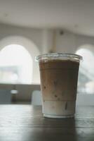 een glas van bevroren latte koffie geserveerd Aan de houten tafel in een koffie winkel foto