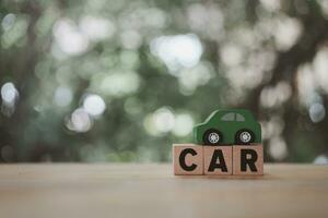 auto houten tekst geplaatst Aan een groen speelgoed- auto. de concept van een auto met kopiëren ruimte foto