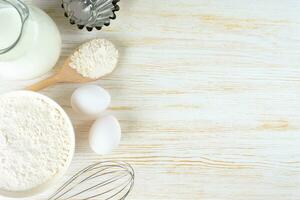 bakken ingrediënten meel, eieren, melk, bakvormen Aan wit houten achtergrond met kopiëren ruimte foto