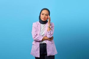 uitgeputte aziatische vrouw die haar pijnlijke oog over blauwe achtergrond aanraakt