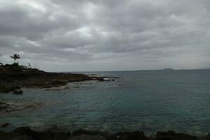 kust landschap met oceaan strand en blauw lucht Aan de eiland van Lanzarote in Spanje foto