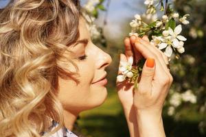 close-up van vrouwelijk gezicht, vrouw die witte bloemen snuift foto