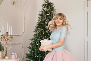 jonge vrouw versiert kerstboom met kerstspeelgoed foto