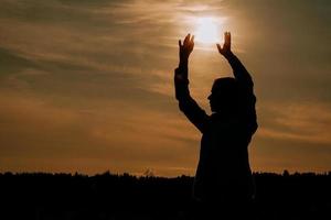 vrouw genieten van zonsondergang. vrouwelijk silhouet in het veld bij zonsondergang foto