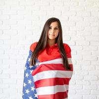 mooie jonge vrouw met Amerikaanse vlag op blauwe achtergrond foto