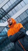 jonge man in oranje werkuniform - glazen gebouw op achtergrond foto