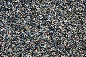 een dichtbij omhoog van een grind strand met rotsen en steentjes foto
