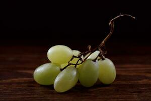 een klein bundel van rijp groen druiven Aan een houten bord. foto