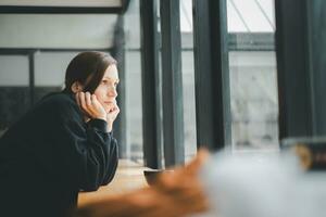 verdrietig vrouw zittend door de venster op zoek buiten foto