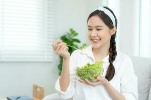 gezond voedsel. mooi vrouw meisje glimlachen genieten eten vers groente salade Aan ontbijt Gezondheid. gelukkig Aziatisch vrouw mooi zo emotie. diëten, ontgiften, eetpatroon, verliezen gewicht, schoon eten, vegetarisch, voedingsdeskundige foto