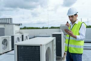 Aziatisch onderhoud ingenieur werk Aan de dak van fabriek. aannemer inspecteren compressor systeem en plannen installatie van lucht staat systemen in bouw. technologie, walky spraakzaam, onderhoud foto