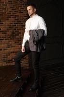 stijlvolle jonge zakenman in wit overhemd houdt een jas vast foto