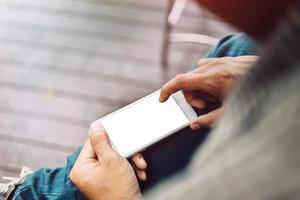 zakenmanhand die mobiele telefoon met behulp van bij koffiewinkel in ochtendlicht foto