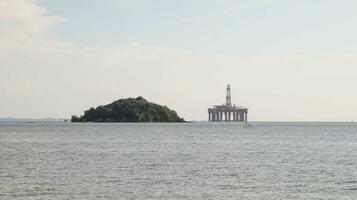 offshore olie platform boren plaats of olie tuigage project gezien ver in de midden- van de zee en een eiland. foto