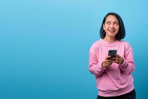 vrolijke jonge aziatische vrouw die smartphone vasthoudt en gelukkig opzij kijkt foto