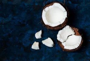 open kokosnoot ligt op een donkerblauwe achtergrond naast gebroken stukken foto
