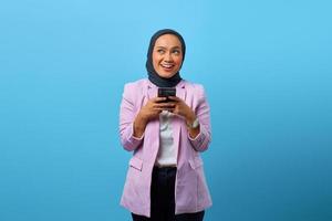 vrolijke aziatische vrouw houdt mobiele telefoon vast en kijkt omhoog foto