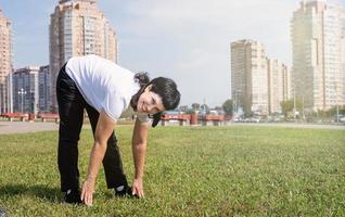 Glimlachende senior vrouw die zich buiten in het park aan het opwarmen is foto