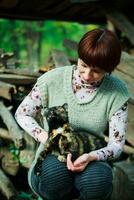 een vrouw is Holding een grijs dakloos katje in haar armen. de katje looks Bij de vrouw wie opgeslagen hem trouw. nemen de dier van de schuilplaats. foto