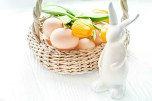 Pasen konijn keramisch in de buurt de mand met Pasen eieren. helder feestelijk achtergrond foto