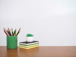 kantoor bureau tafel, leerling creatief bureaublad met kleurrijk briefpapier, hardcover boek, ingemaakt cactus. kopiëren ruimte voor tekst, terug naar school, onderwijs concept foto