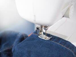 dichtbij omhoog naaien machine naaien naad van blauw denim jean. foto