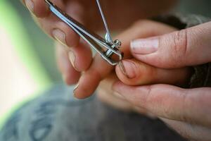 een knus moment van echt leven. mam duurt zorg van de baby en bezuinigingen haar nagels met tang voor nagels. foto