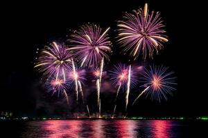 geweldig mooi kleurrijk vuurwerk op de feestavond, te zien op het zeestrand met veelkleurige reflectie op water foto