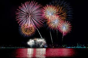 geweldig mooi kleurrijk vuurwerk op de feestavond, te zien op het zeestrand met veelkleurige reflectie op water foto