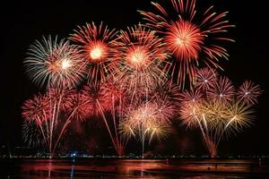 geweldig mooi kleurrijk vuurwerk op de feestavond, te zien op het zeestrand met veelkleurige reflectie op water foto