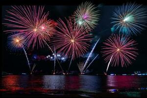 geweldig mooi kleurrijk vuurwerk op de feestavond, te zien op het zeestrand met veelkleurige reflectie op water foto