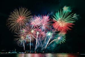 geweldig mooi kleurrijk vuurwerk op de feestavond, te zien op het zeestrand met veelkleurige reflectie op water foto