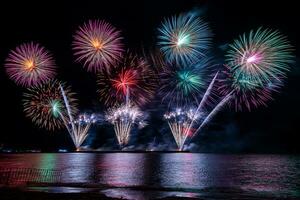 geweldig mooi kleurrijk vuurwerk op de feestavond, te zien op het zeestrand met veelkleurige reflectie op water foto