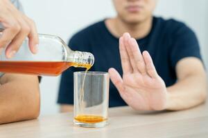 Mens weigert zeggen Nee en vermijden naar drinken een alcohol whisky , stoppen hand- teken mannelijk, alcoholisme behandeling, alcohol verslaving, stoppen drank, hou op drinken alcohol. weigeren glas likeur, ongezond, afwijzen foto