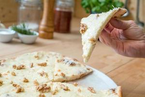 het eten van een plakje Italiaanse pizza gorgonzola kaas en walnoten foto