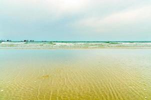 het uitzicht op het zandstrand en de zeegolf met rots en rif op de ochtend? foto